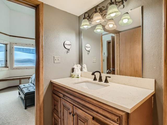 bathroom with a textured wall, vanity, and baseboards