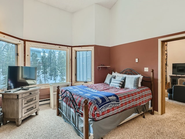 bedroom featuring carpet floors, a baseboard heating unit, and a high ceiling