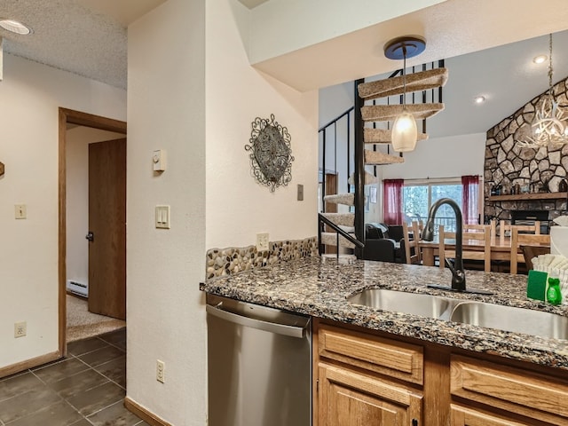 kitchen featuring dishwasher, dark stone countertops, baseboard heating, a textured ceiling, and a sink