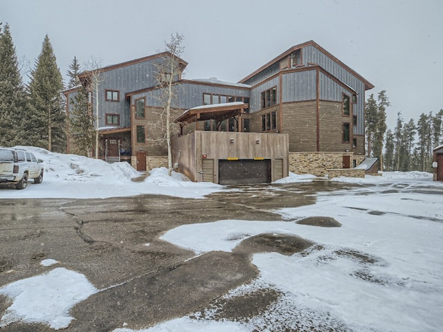 snow covered rear of property with a garage