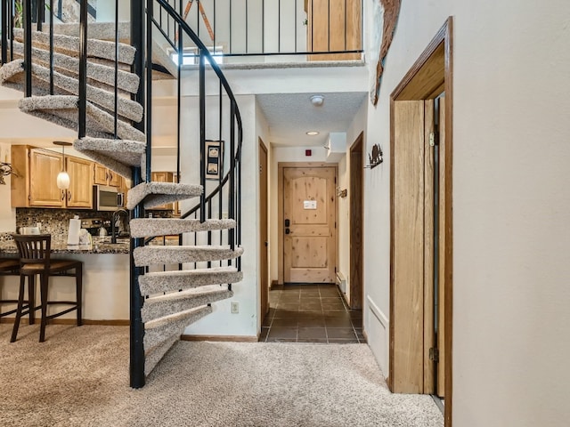 hall with stairs, carpet floors, a high ceiling, and baseboards