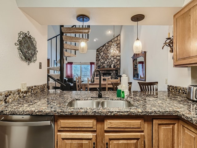 kitchen featuring dishwasher, dark stone counters, a fireplace, and a sink