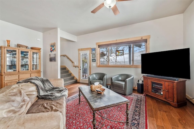 living room with stairs, a ceiling fan, and wood finished floors