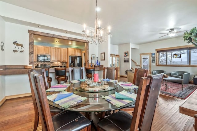 dining room featuring ceiling fan with notable chandelier, baseboards, and light wood finished floors