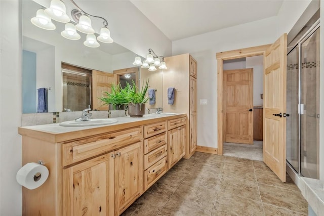 full bathroom with double vanity, a stall shower, baseboards, and a sink