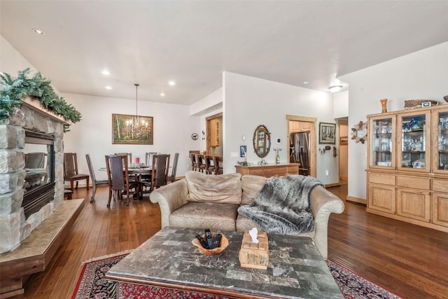 living area with a stone fireplace, recessed lighting, dark wood-style floors, and a chandelier