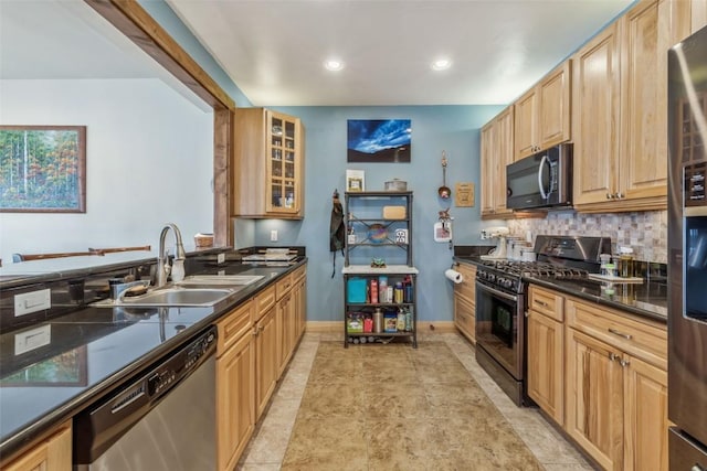 kitchen featuring a sink, backsplash, stainless steel appliances, glass insert cabinets, and baseboards