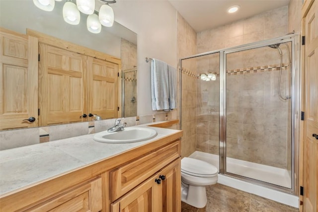 bathroom with toilet, a stall shower, and vanity