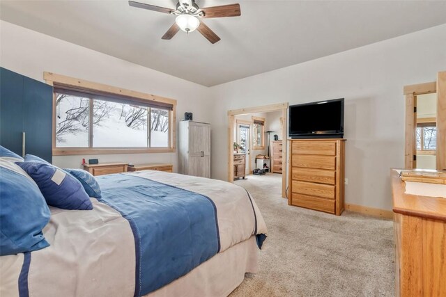 bedroom featuring ceiling fan, multiple windows, baseboards, and light carpet