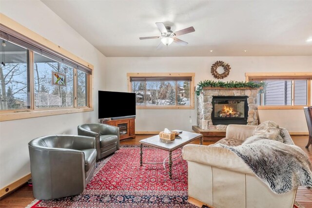 living room with baseboards, a ceiling fan, wood finished floors, and a fireplace