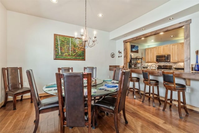 dining space with recessed lighting, wood finished floors, and a chandelier