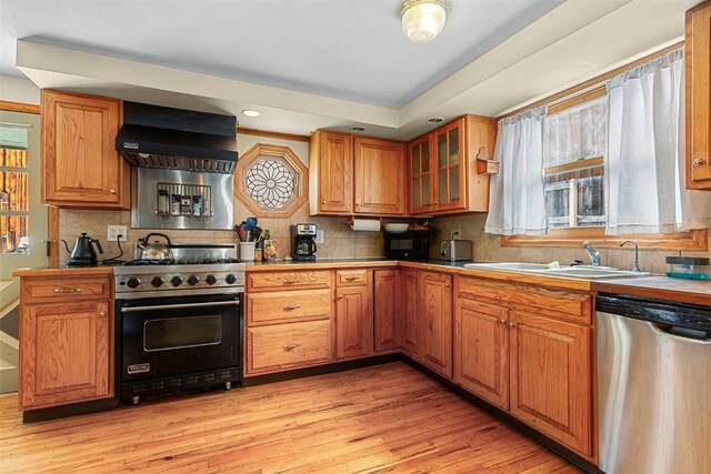 kitchen featuring backsplash, wall chimney exhaust hood, high end range, and stainless steel dishwasher