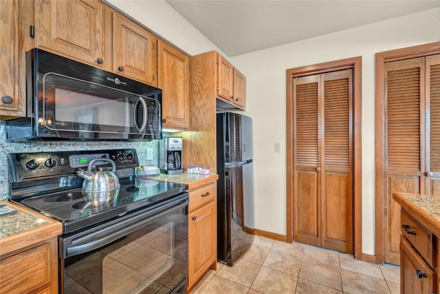 kitchen featuring black appliances, light tile patterned flooring, and light countertops