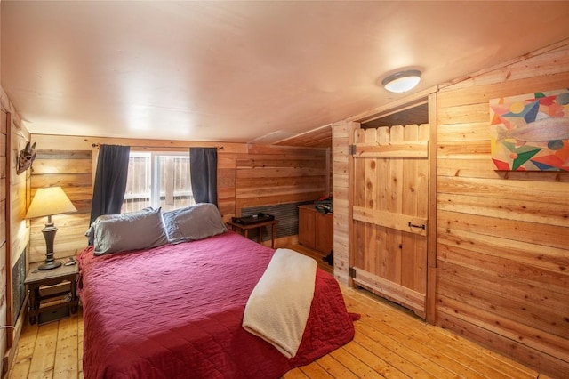 bedroom featuring light hardwood / wood-style flooring, vaulted ceiling, and wood walls