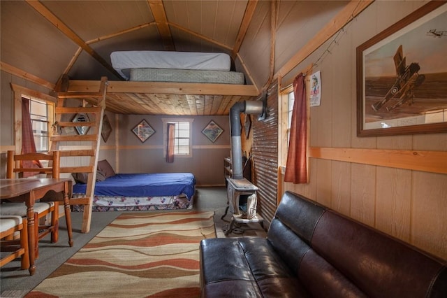 bedroom with a wood stove, wood walls, carpet, and vaulted ceiling