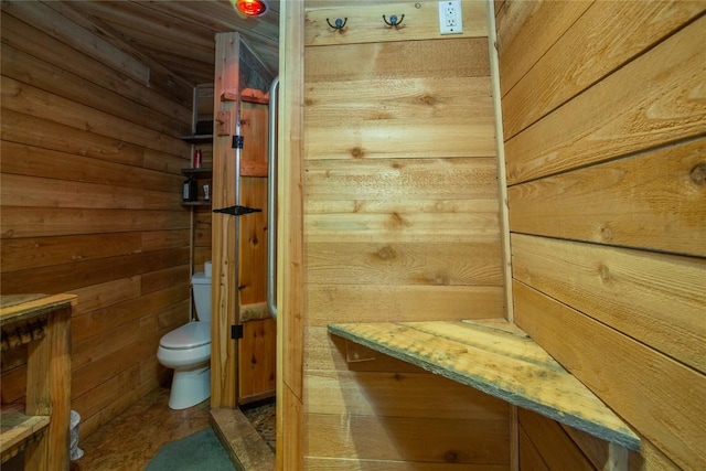 bathroom with toilet and wooden walls