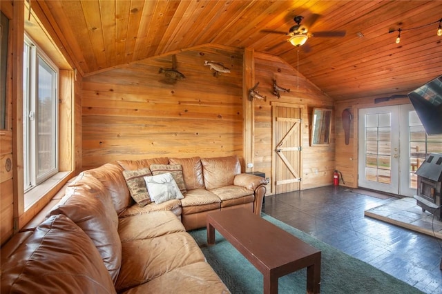 living room featuring wooden walls, ceiling fan, a healthy amount of sunlight, and vaulted ceiling