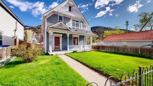 victorian house featuring a front lawn, a balcony, fence, and covered porch