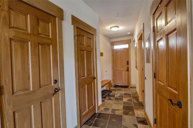 corridor featuring stone finish floor and baseboards