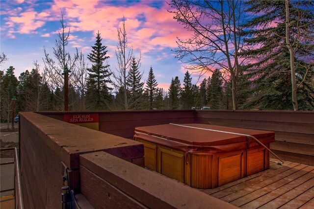 deck at dusk featuring a hot tub