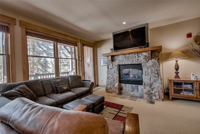 living area featuring carpet floors, a wealth of natural light, and a stone fireplace