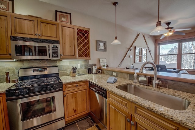 kitchen with stainless steel appliances, a sink, backsplash, and light stone countertops