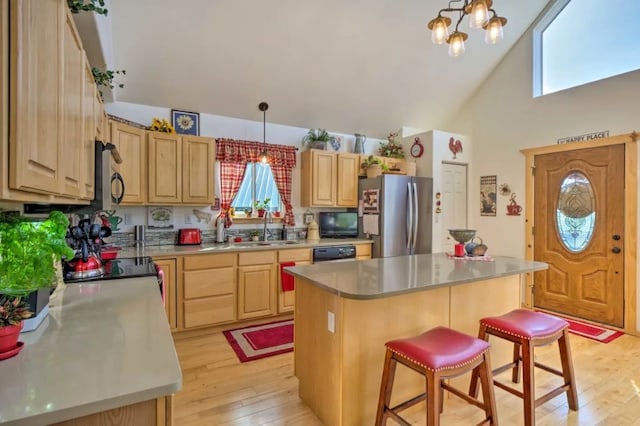 kitchen featuring a breakfast bar, sink, pendant lighting, a center island, and stainless steel refrigerator