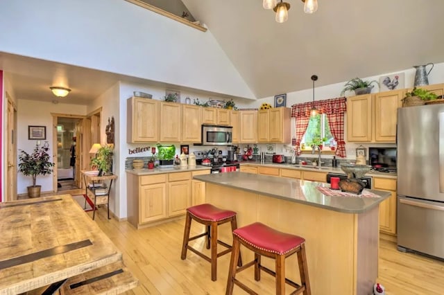 kitchen featuring a center island, light brown cabinetry, a breakfast bar area, and appliances with stainless steel finishes