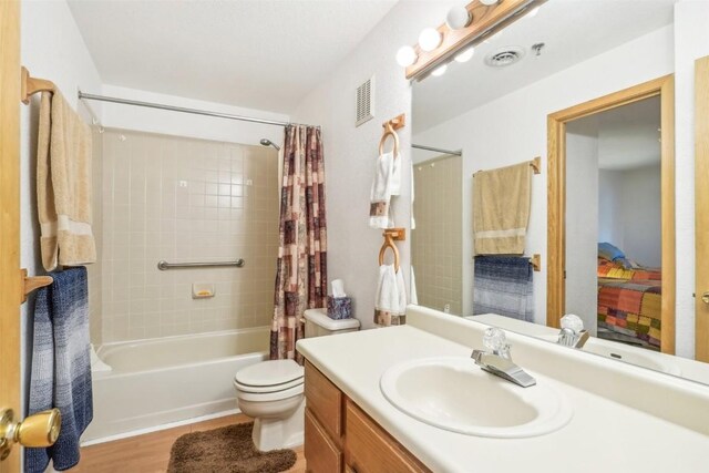 full bathroom featuring hardwood / wood-style floors, shower / bath combo, toilet, and vanity