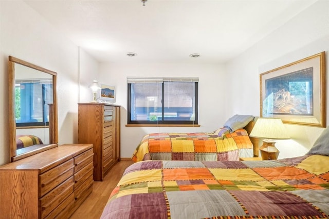 bedroom with multiple windows and light hardwood / wood-style flooring