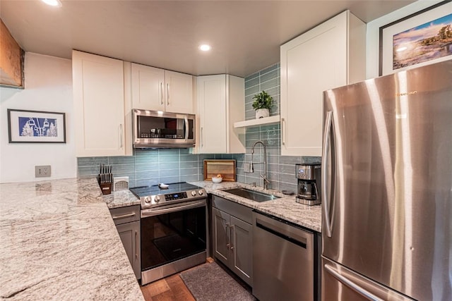 kitchen featuring light stone counters, white cabinetry, sink, and appliances with stainless steel finishes