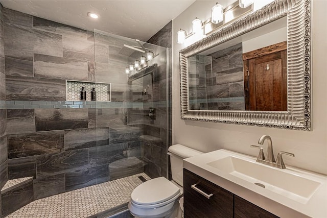 bathroom featuring a tile shower, vanity, and toilet