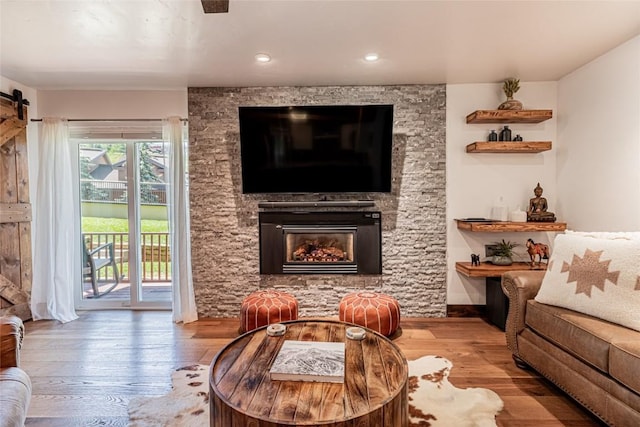 living room featuring a barn door, a fireplace, and light hardwood / wood-style flooring