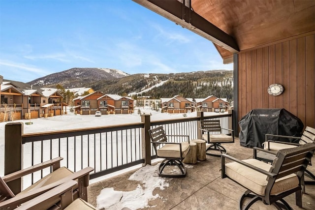 snow covered back of property featuring a grill and a mountain view