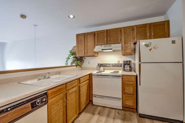 kitchen with white appliances, under cabinet range hood, light countertops, and a sink