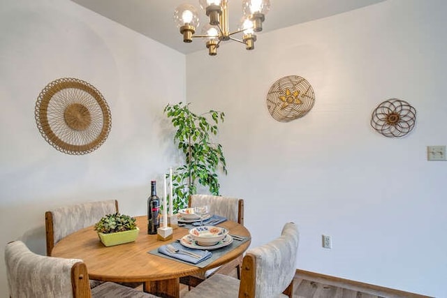 dining space with wood finished floors and an inviting chandelier