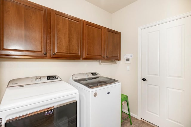 laundry room featuring washer and dryer, light tile patterned floors, and cabinets