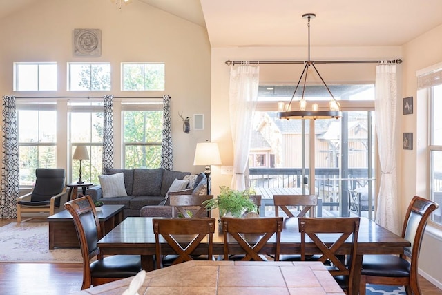 dining area with dark hardwood / wood-style floors, lofted ceiling, and an inviting chandelier