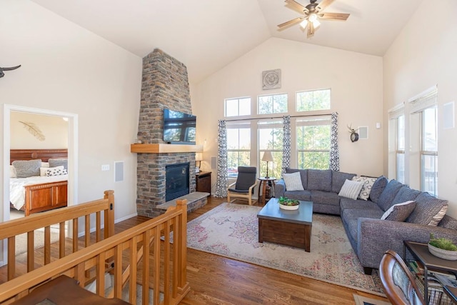 living room with a large fireplace, plenty of natural light, ceiling fan, and dark wood-type flooring