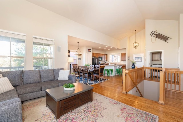 living room with light hardwood / wood-style floors and high vaulted ceiling