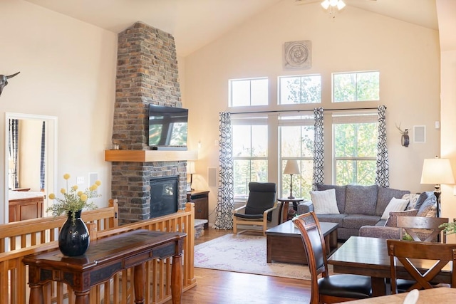 living room with ceiling fan, a fireplace, high vaulted ceiling, and dark wood-type flooring