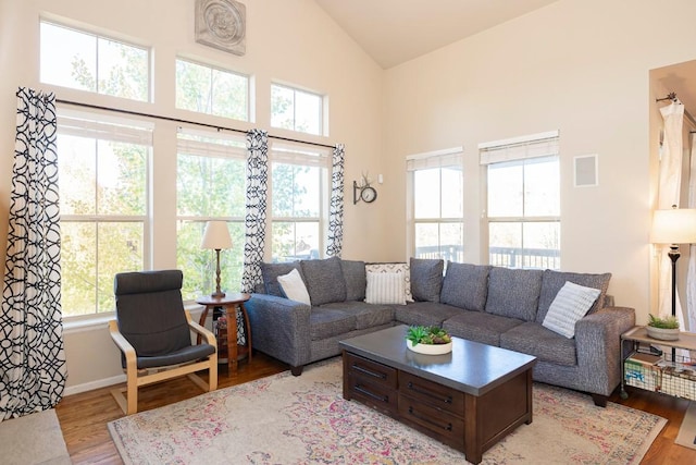 living room with high vaulted ceiling and light hardwood / wood-style flooring