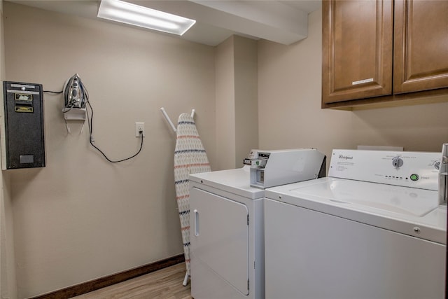 clothes washing area with cabinets, light wood-type flooring, and washer and dryer