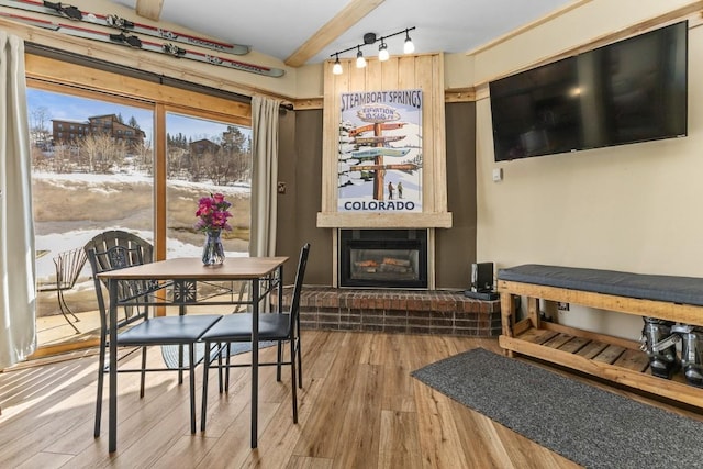 dining area with rail lighting, wood finished floors, and a large fireplace