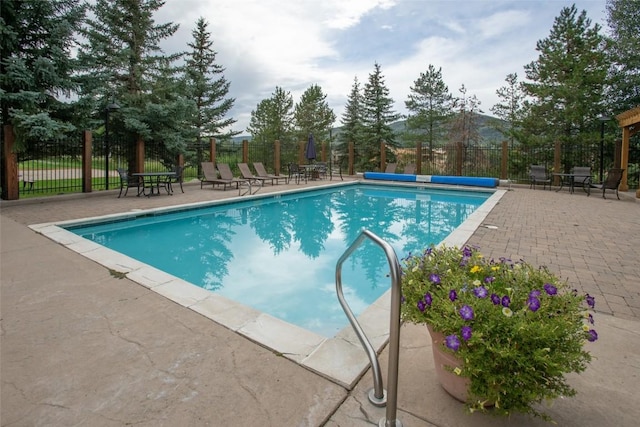 community pool with a patio area and fence