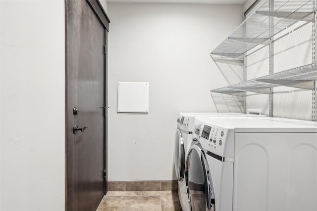 clothes washing area with washer and dryer, laundry area, and baseboards