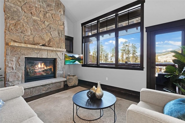 living room with a fireplace, baseboards, and vaulted ceiling