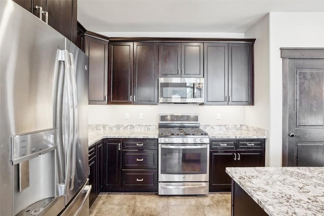 kitchen featuring light stone counters, dark brown cabinets, and appliances with stainless steel finishes