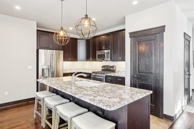 kitchen with a center island with sink, decorative light fixtures, sink, and appliances with stainless steel finishes