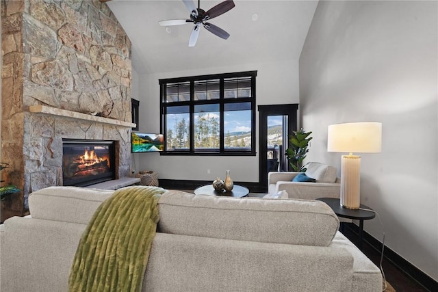 living room featuring a ceiling fan, a fireplace, baseboards, and high vaulted ceiling